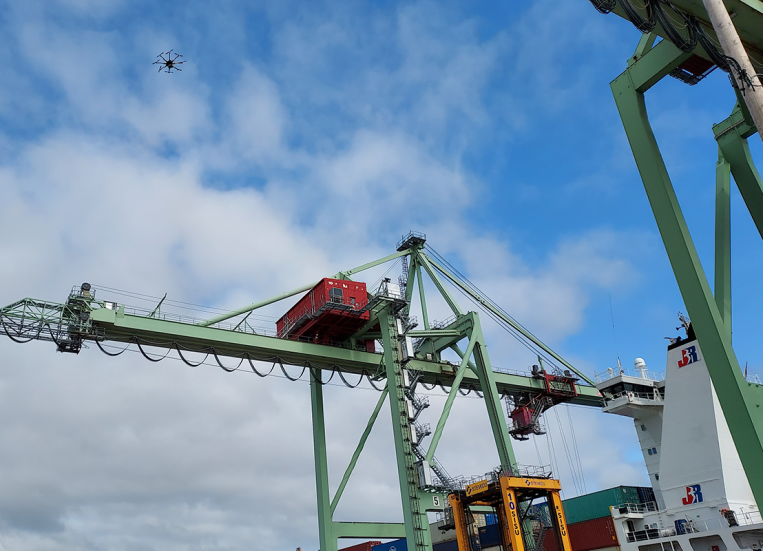 Kuvassa drone lentää korkealla sataman yllä.