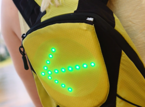 Kuvassa keltainen reppu, jossa vihreät, valaistut led-valot muodostavat nuolikuvion.