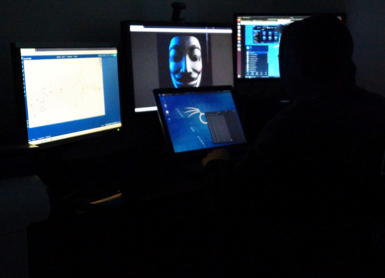 Merenkulun kyberturvallisuus -julkaisun tummassa kansikuvassa on tietokoneiden näyttöjä, joista heijastuu ”mustahattuhakkerin”, eli pahansuopaisen verkkorikollisen kuva.