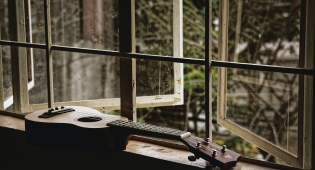 Yksinäinen ukulele avoimien ikkunoiden edessä.