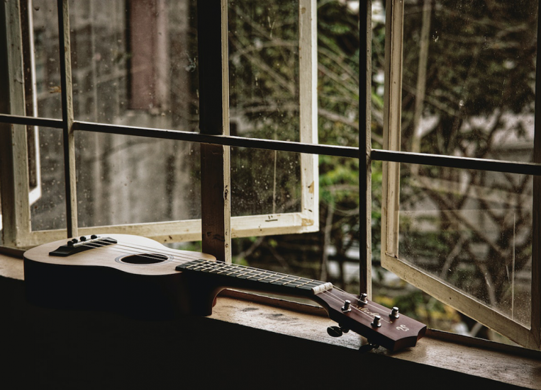 Yksinäinen ukulele avoimien ikkunoiden edessä.