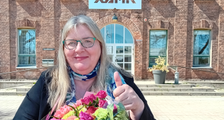 Kuvassa eläkkeelle jäävä oppilaitospastori Jaana Pietiläinen Xamkin Kouvolan kampuksen pääoven edessä.