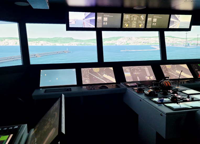 Kuvassa on laivan komentosiltasimulaattori oikeilla laitteilla. Ikkunat on korvattu näytöillä, joista näkyy sataman virtuaalimalli.