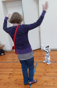 Nainen tanssii lattialla pienen Zora-robotin tahdissa.