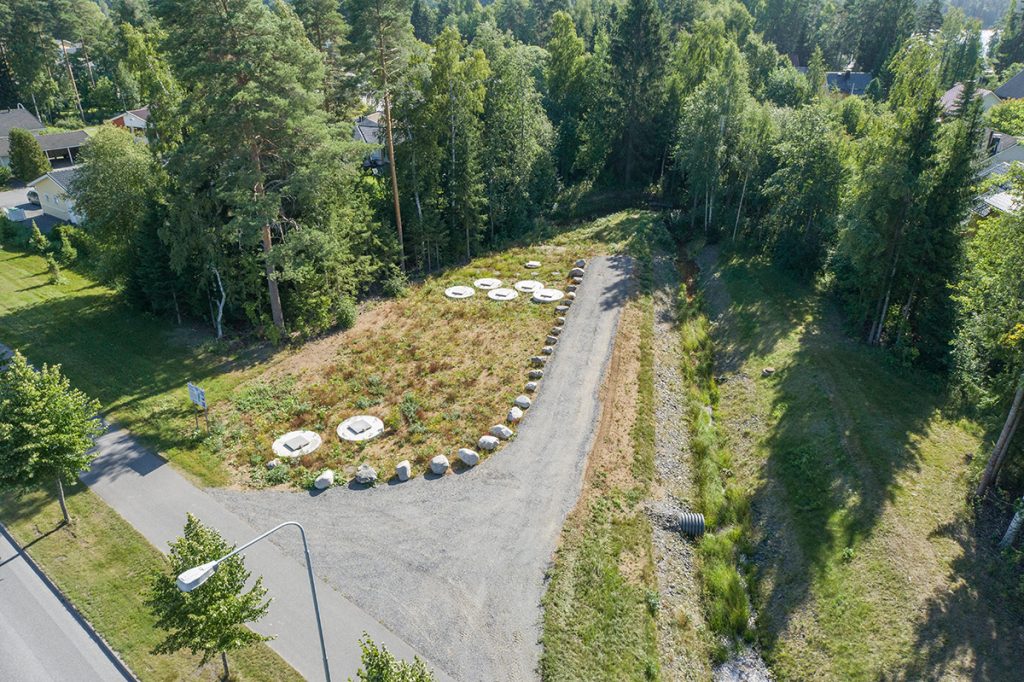 Ilmakuvassa nähdään kaivonkansia nurmialueella. Kaivonkansien vieressä kulkee huoltotie.