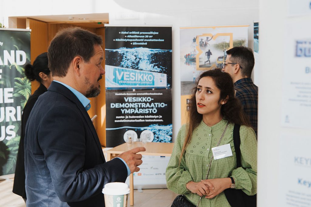 Valokuva Water Weekin tapahtumasta. Kuvassa ihmisiä ja taustalla AWE-hankkeen roll up.